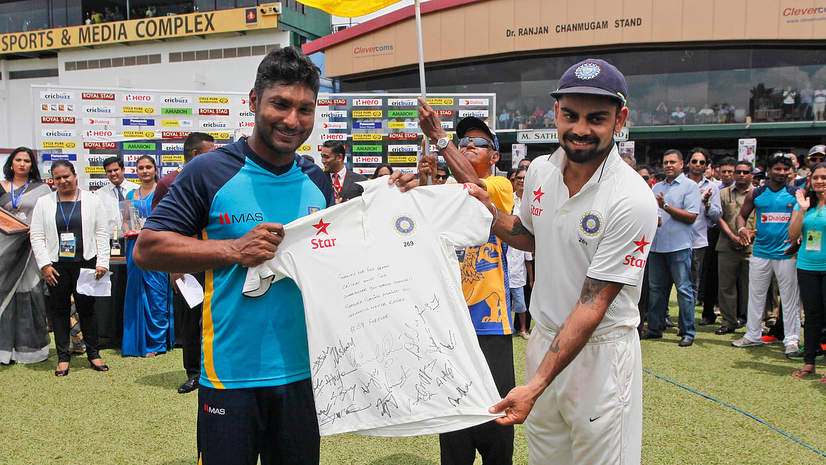 Virat Kohli, right, presents a souvenir to Sri Lankan cricketer Kumar Sangakkara at the end of his farewell test. (Photo: AP)