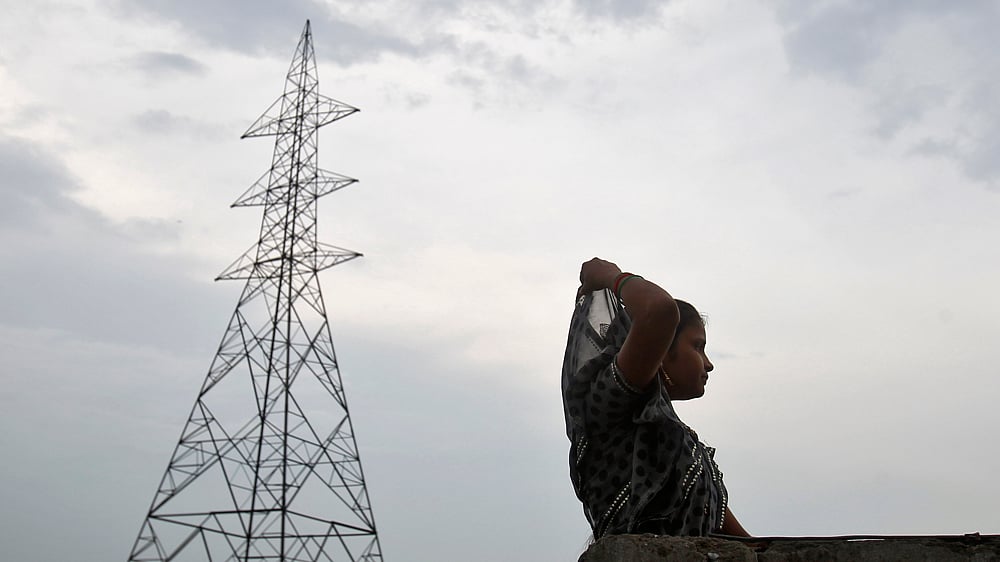 A woman stands on the rooftop of her house next to a high tension electric pylon on the outskirts of New Delhi September 14, 2012. (Photo: Reuters)