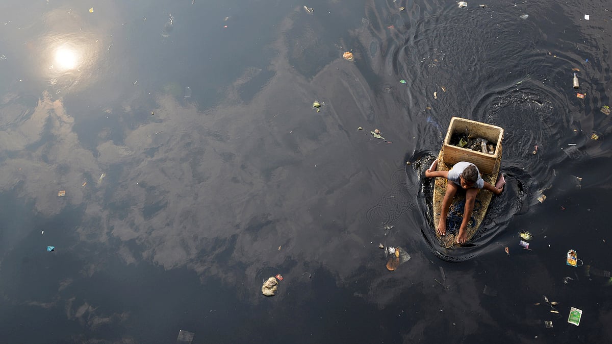 A woman paddles in a makeshift boat as she collects recyclable trash from a polluted river in Navotas city, Philippines.&nbsp; (Photo: Reuters/Ezra Acayan)