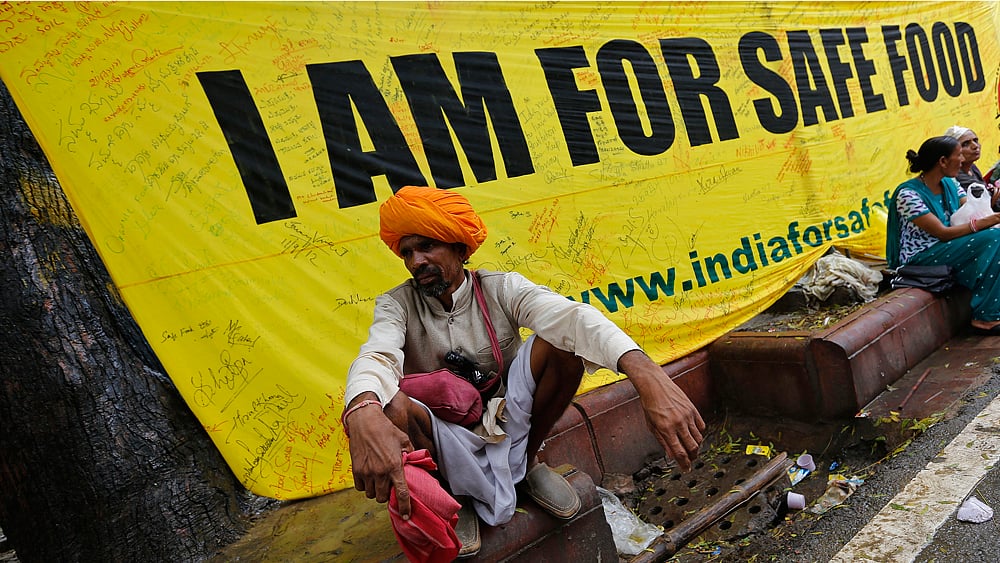 A farmer squats along a footpath near a banner during a day-long protest in New Delhi August 8, 2013. (Photo: Reuters)