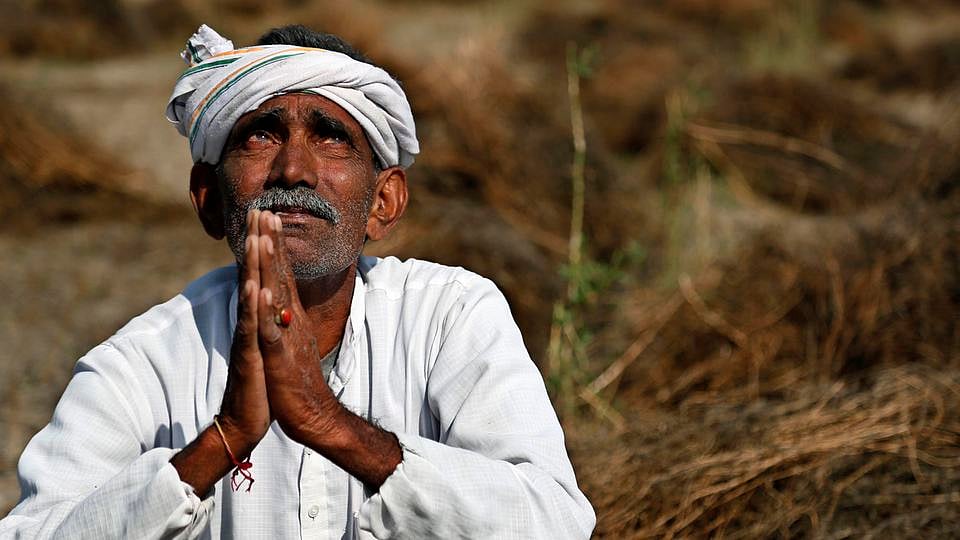 An Indian farmer looks skyward as he sits in his field with wheat crop that was damaged in unseasonal rains and hailstorm at Darbeeji village, in the western Indian state of Rajasthan. (Photo: AP)