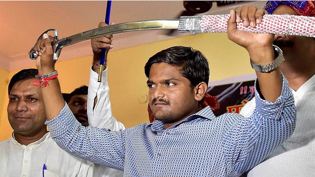 Hardik Patel, convener of Patidar Anamat Andolan Samiti (PAAS) brandishes a sword presented to him at a function organized by Gujjars to honour him in New Delhi. (Photo: PTI)