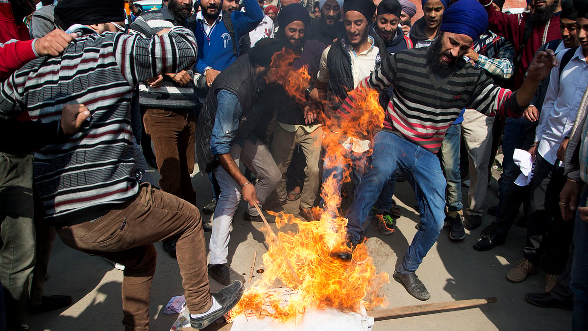 Kashmiri Sikhs kick a burning effigy of Gurmeet Ram Rahim Singh, chief of Dera Sacha Sauda. (Photo: AP)
