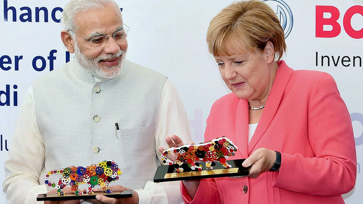 Prime Minister Narendra Modi and German Chancellor Angela Merkel with Make in India logo models at the Bosch Vocational Center in Bengaluru on Tuesday. (Photo: PTI)