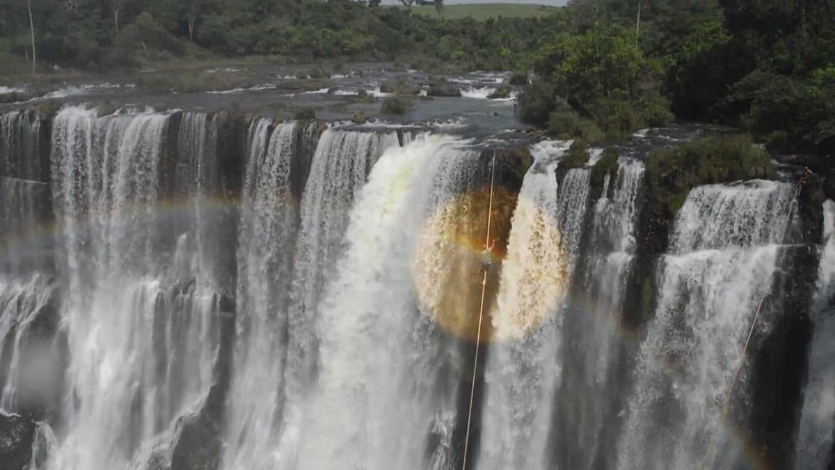 A spectacular rainbow arches over a Brazilian highliner as he tries to cross a waterfall.