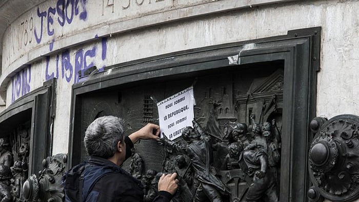 A man pins up a placard that says “We are the Republic, we are liberty” in the aftermath of the brutal attacks in Paris on Friday. (Photo: Karan Sarnaik)