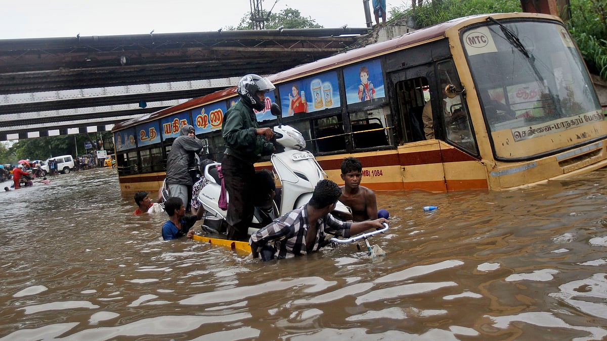 People help a man carry his two-wheeler on a cycle cart as they wade through a waterlogged subway in Chennai, India on Monday, Nov 9, 2015. (Photo: AP)