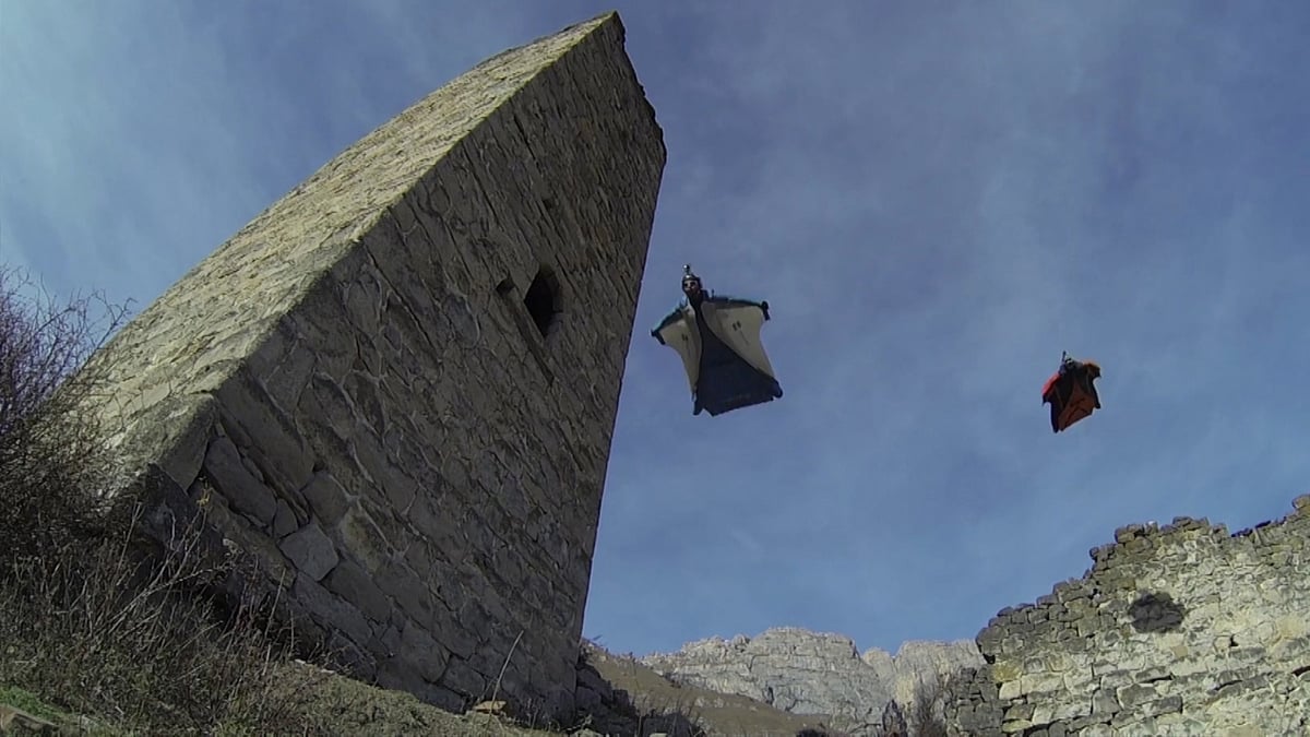 Base jumpers Ratmir Nagimyanov and his friend had a lucky escape as they soared over the rocky outcrops in the North Caucasus, Ingushetia, when they flew past very close to an old tower. (Photo: AP/Caters News screengrab)