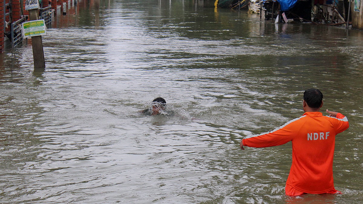 An NDRF official (right) arrives to rescue a boy who fell while wading through flood waters in Chennai. (Photo: <b>The Quint</b>)