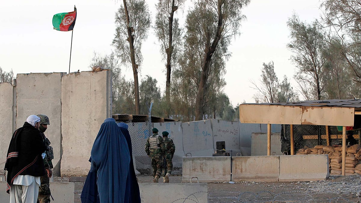 Civilians wait as Afghan security forces guard  the main gate of Kandahar civilian airport. (Photo: AP)