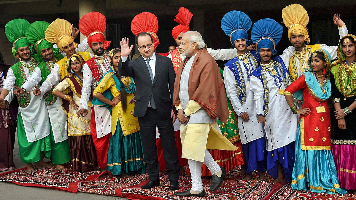 Prime Minister Narendra Modi looks on as French President Francois Hollande waves, as they stand with Indian folk dancers at the government museum and art gallery in Chandigarh on Sunday, 24 January 2016. (Photo: AP) 