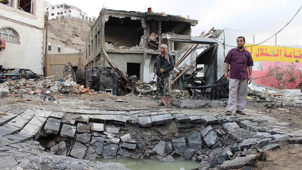 Men stand next to a crater made by a car bomb attack near the presidential palace in the southern port city of Aden. (Photo: AP)