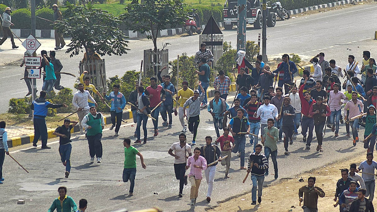 Protesters run some with sticks during a pro caste quota protest in Rohtak, 70 kilometers from New Delhi. (Photo: AP)