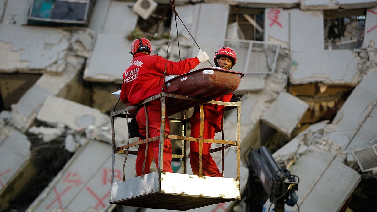 Two emergency workers carry a victim recovered from a collapsed building in Tainan, Taiwan, Sunday, February 07. (Photo: AP) 