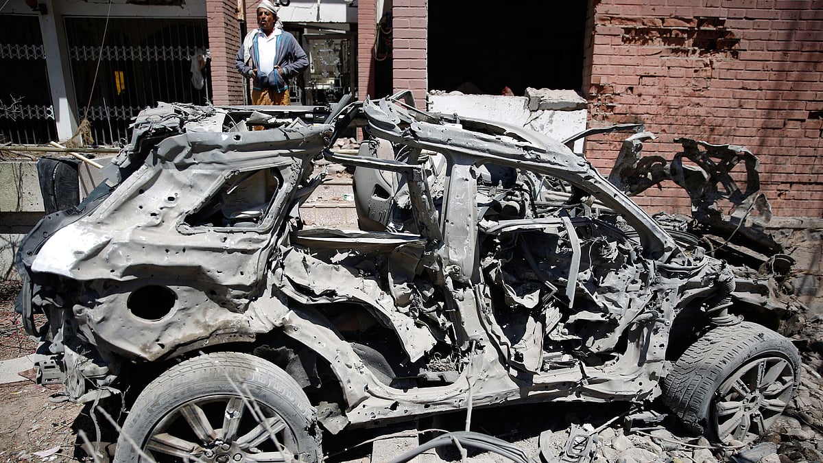 A Yemeni man stands next to a damaged vehicle after an airstrike by Saudi-led coalition in Sanaa, Yemen, on Saturday, 27 Feb 2016.