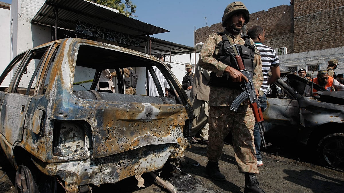 A Pakistani soldier walks past damaged vehicles at the site of a deadly suicide bombing in Charsadda. (Photo: AP)