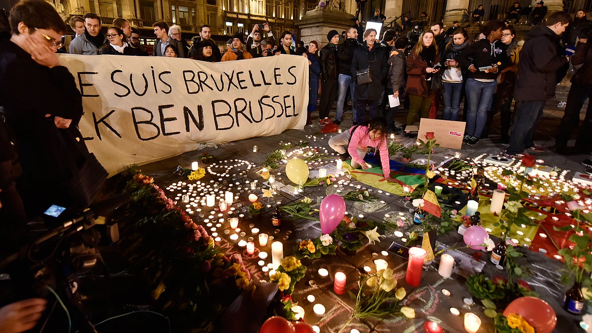 People holding a banner reading “I am Brussels” behind flowers and candles to mourn for the victims at Place de la Bourse in the centre of Brussels, 22 March, 2016. (Photo: AP)
