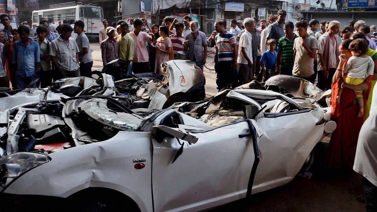 People gather around the mangled remains of a car pulled out from under the debris . (Photo: PTI)