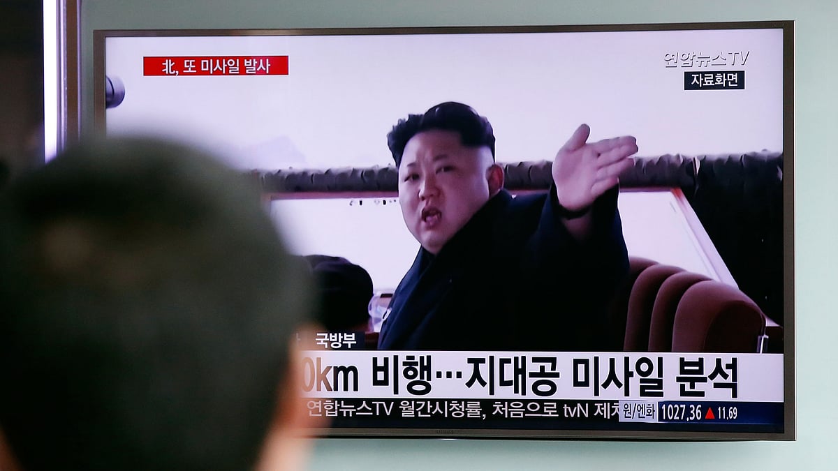 A man watches a TV news program showing file footage of North Korean leader Kim Jong-un.