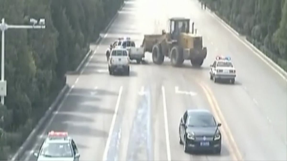 Police chase the bulldozer driver as he crashes into cars and people deliberately. (Photo: AP/Newsflare Screengrab)