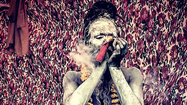A Nagasadhu lights up his chillum inside his akhada at the Simhastha Ujjain Kumbh Mela 2016 (Photo: Rishika Baruah/ <b>The Quint</b>)