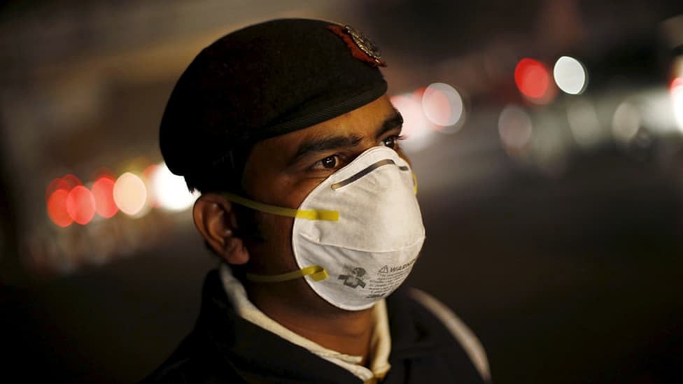 A traffic policeman wears a mask to protect himself from dust and air pollution as he stands on a road-divider in New Delhi, 23 December 2015. (Photo: Reuters)