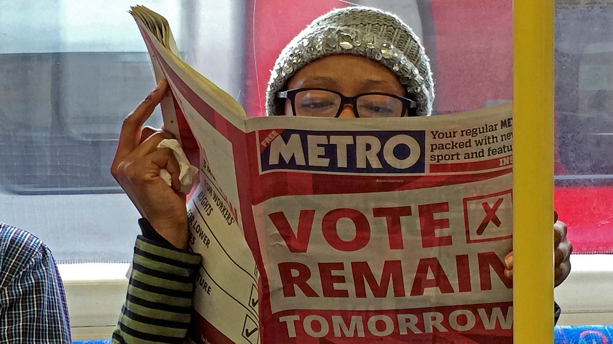 A woman holds up a newspaper which has an advertisement for ‘Remain’. (Photo: Reuters)