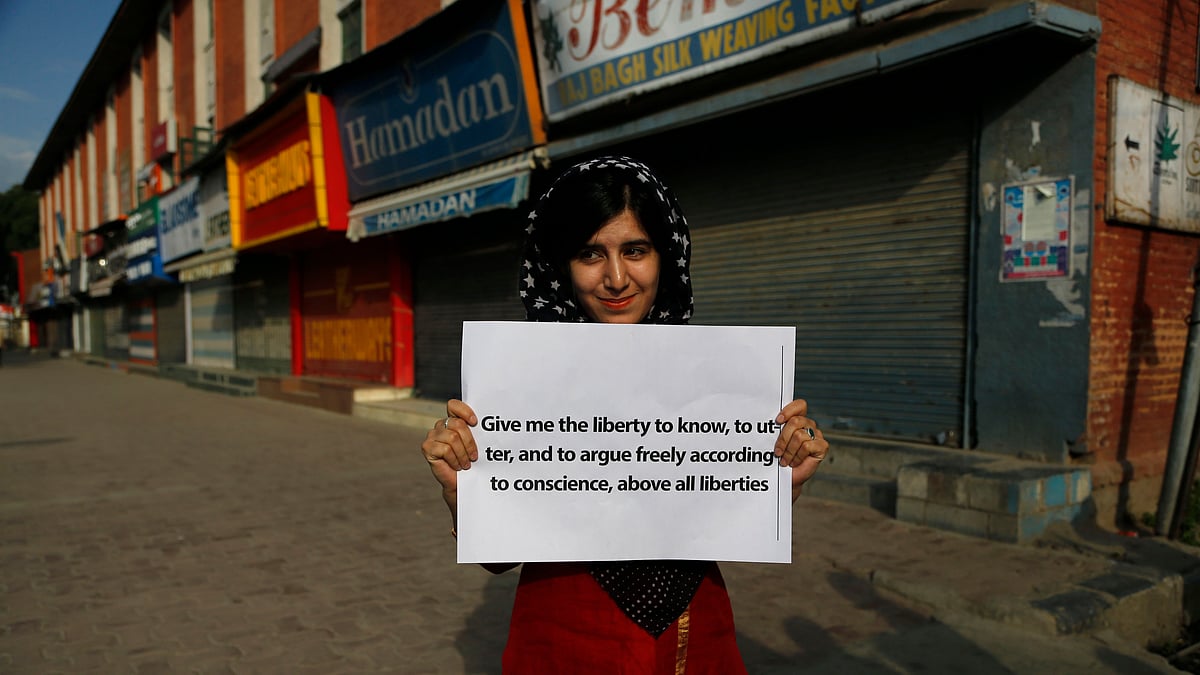 A Kashmiri journalist holds a placard as she along with other journalists protest against the government in Srinagar. (Photo : AP)