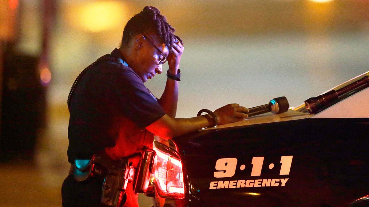 A Dallas police officer takes a moment as she guards an intersection in Dallas. (Photo: AP)