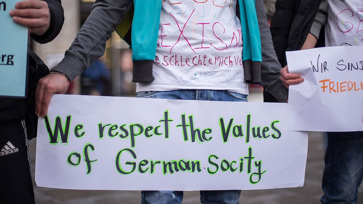 In this Jan. 16, 2016 file photo a participant at the demonstration ‘Syrian refugees say no to the Cologne assaults!’ holds a sign in Cologne, Germany. According to police reports, numerous women were sexually harassed and robbed in front of Cologne central station on New Year’s Eve. (Photo: AP)