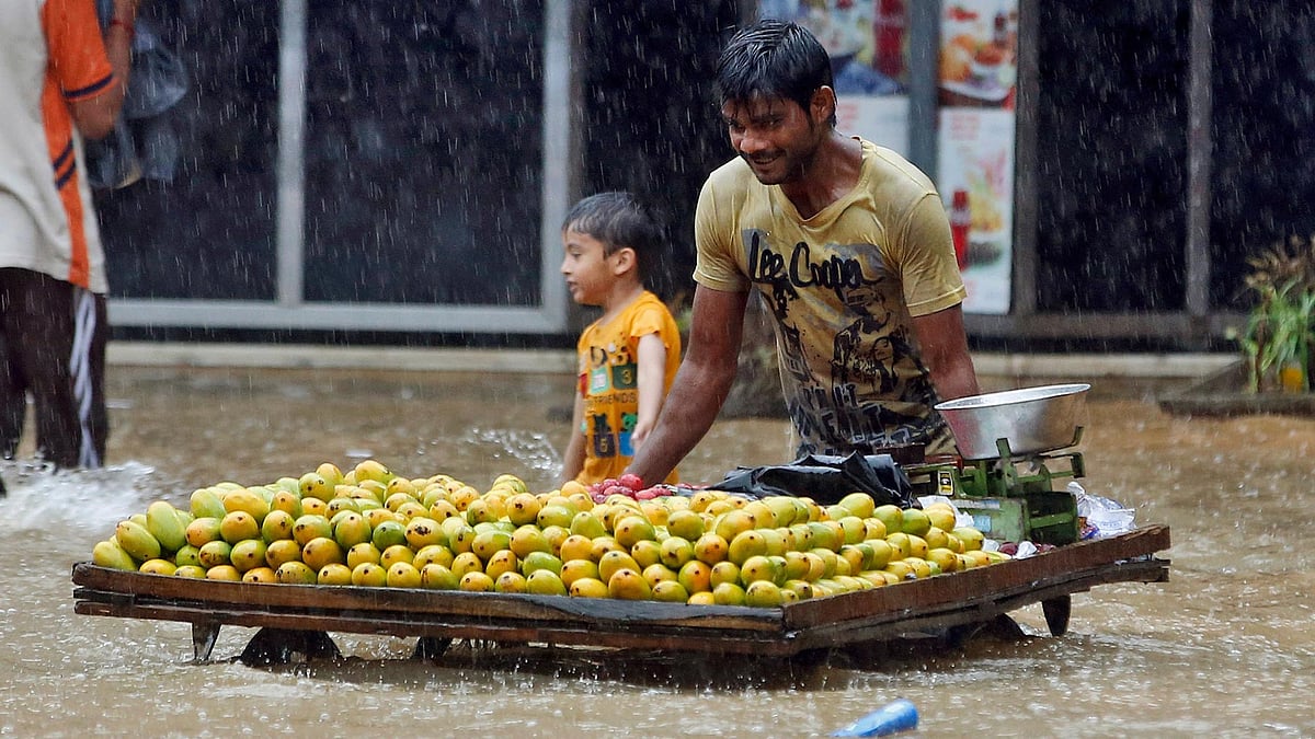 Representational image of a fruit vendor pushes his cart through a flooded street in Mumbai. (Photo: AP)