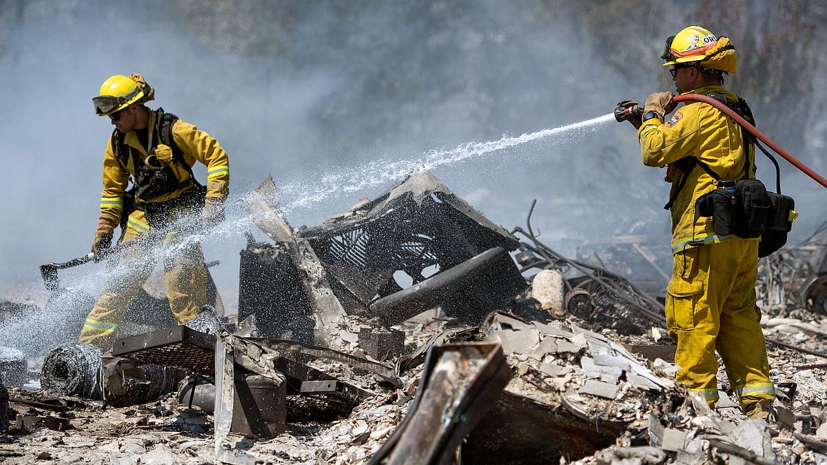 Firefighters douse the smoldering remains of a home in Lower Lake, California, on Monday. (Photo: AP)