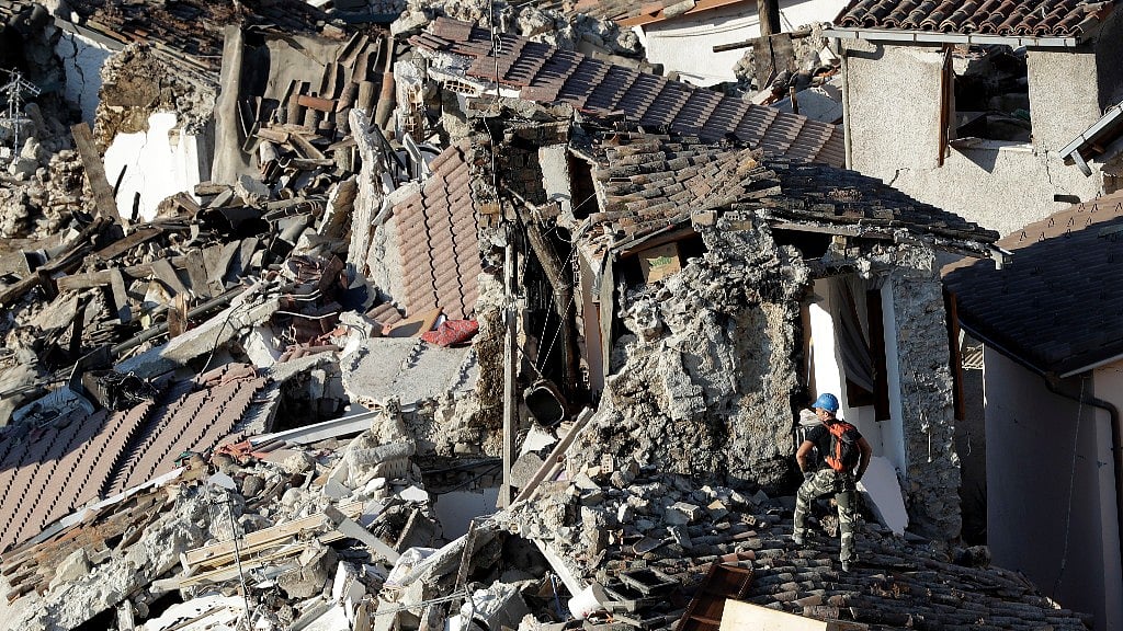 Rescuers make their way through destroyed houses following an earthquake in Italy (Photo: AP)