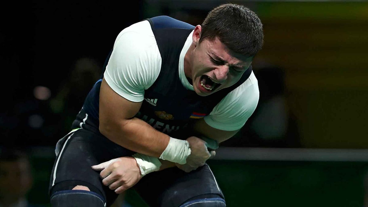 Andranik Karapetyan, of Armenia, yells in pain after injuring his left arm during the men’s 77kg weightlifting competition. (Photo: AP)
