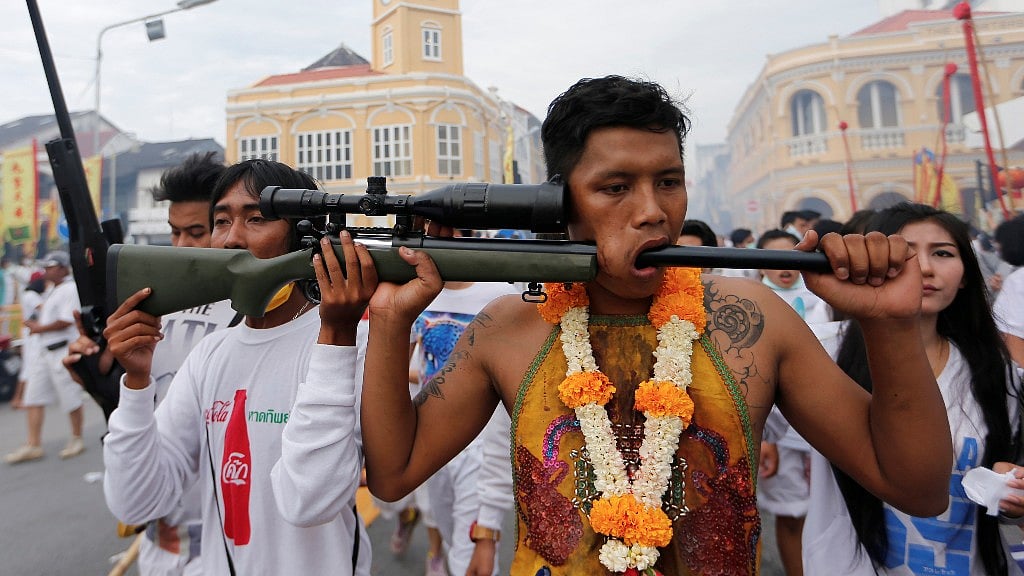 A devotee of the Chinese Bang Neow shrine with a gun barrel pierced through his cheek takes part in a procession celebrating the annual vegetarian festival in Phuket, Thailand (Photo: Reuters)