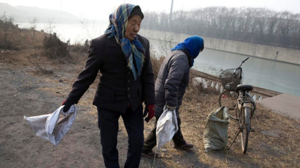 Shen and another villager wait to pick up coal that falls from overfilled coal trucks in northern Hebei province, China’s largest steel-making region. (Photo: AP)