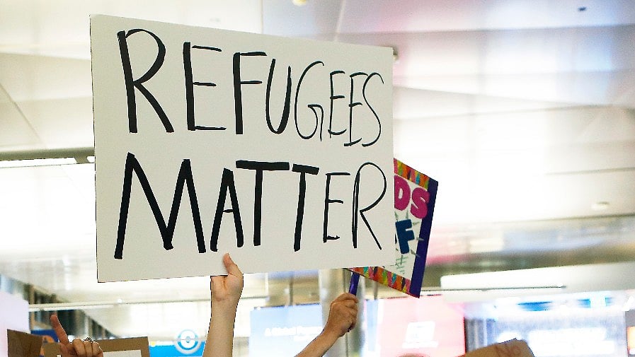 People hold signs of “Refugees Matter” at a protest. (Photo: AP)
