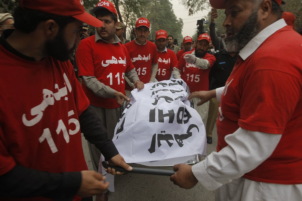 Pakistani volunteers remove a body from the site of a bombing in Peshawar in Pakistan. (Photo: AP)