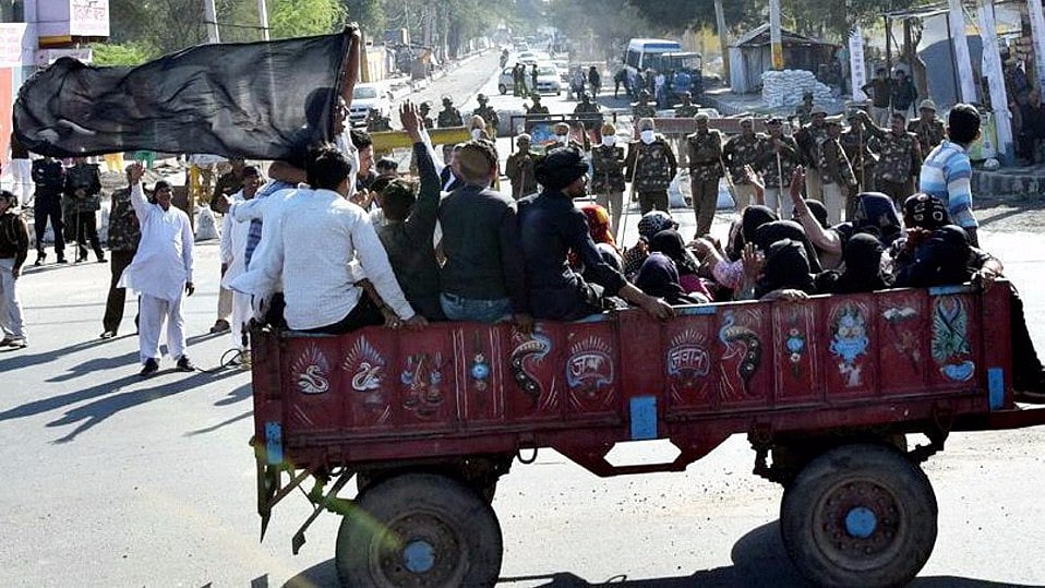 

Jat women wearing black scarf around their face reach a protest site in Jasia Village  in Rohtak on Sunday. Security men guard in the background. (Photo: PTI)