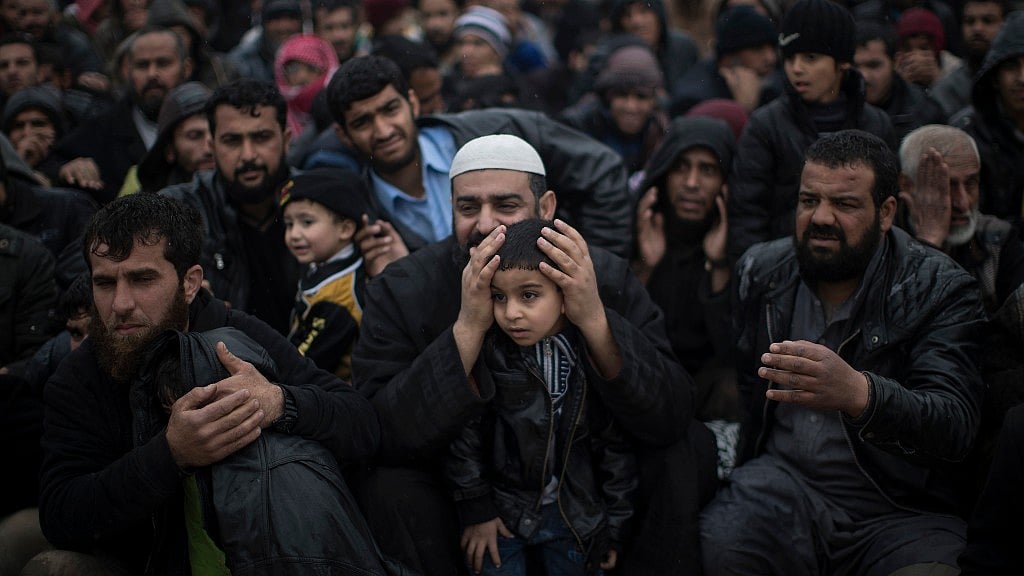 A displaced Iraqi man covers the ears of his son after a weapon was fired in Iraq. (Photo: AP)