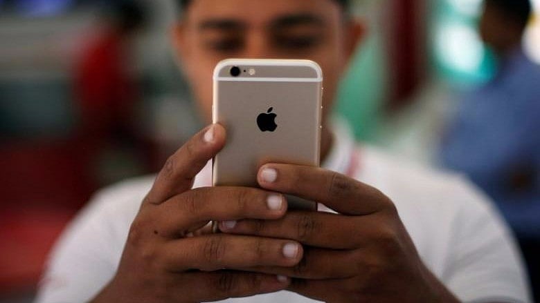 A salesman checks a customer’s iPhone at a mobile phone store in New Delhi.&nbsp;