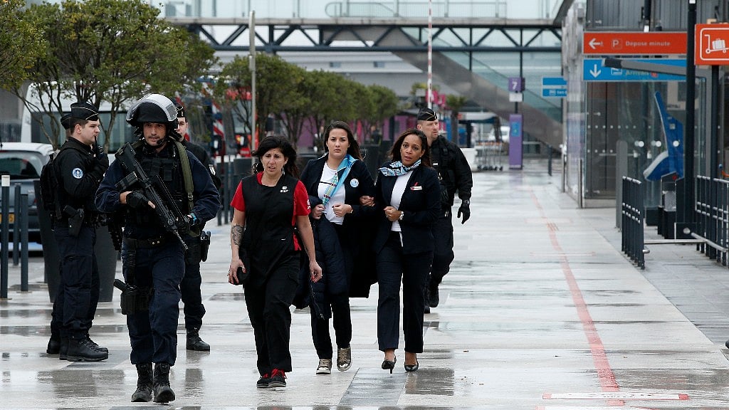 A police officer escorts airport employees outside the Orly airport in Paris. (Photo: AP)