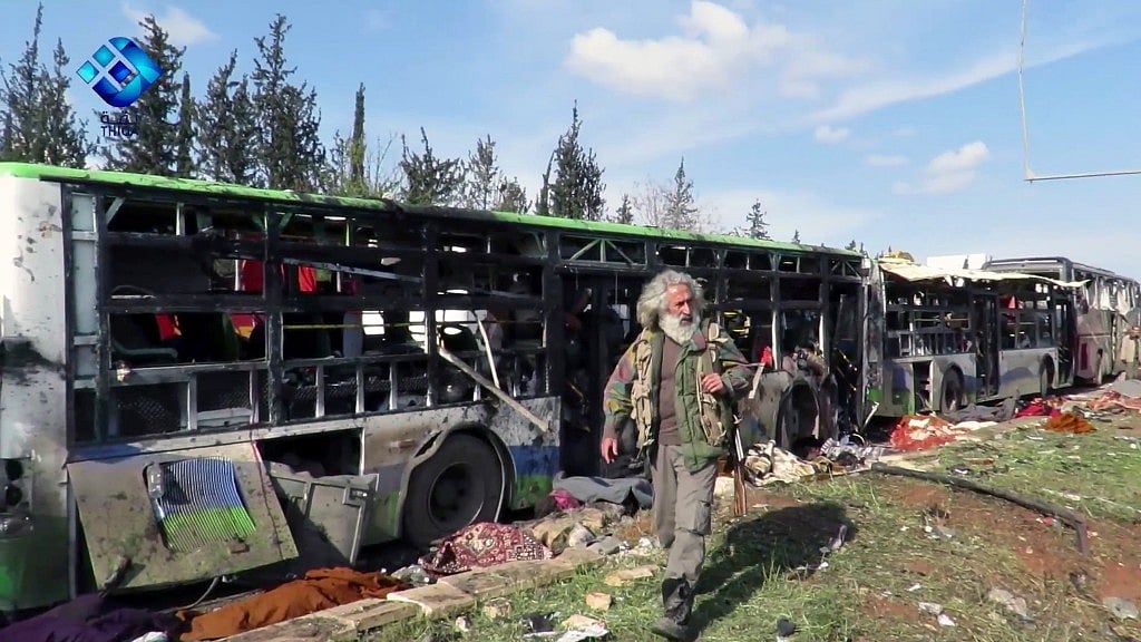This frame grab from video provided by the Thiqa News Agency, shows a gunman passing by the buses that were damaged in a blast outside Aleppo. (Photo Courtesy: AP)