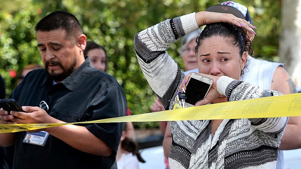Parents and family of North Park Elementary School students stand across the street from the school waiting to hear from their children in California. (Photo: AP)