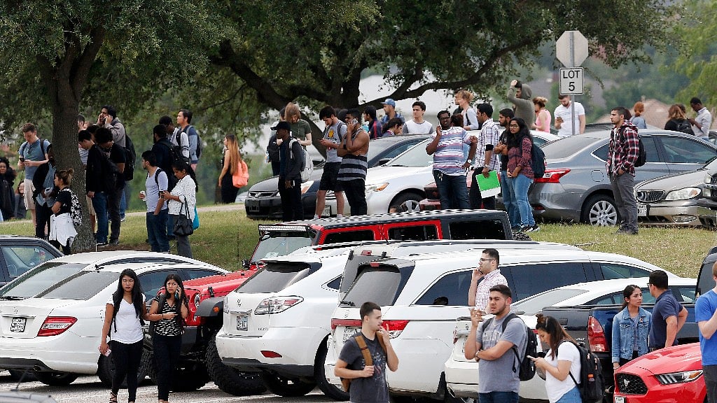 People stand in the parking lot while Irving police officers work at the shooting scene. (Photo: AP)