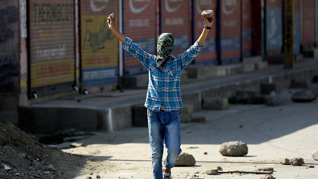 A masked protester shouts freedom slogans before throwing a rock at policemen in Srinagar, 27 May, 2017. (Photo: AP)