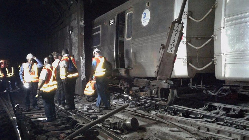 Workers from the New York Metropolitan Transportation Authority examine damaged train tracks, at the scene of the derailment. (Photo: AP)