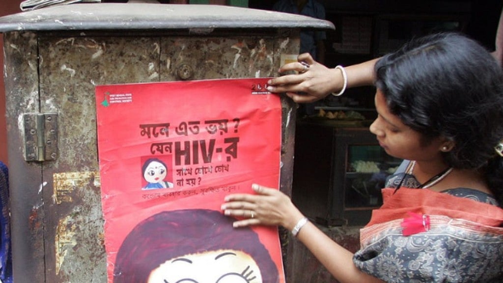 An activist puts up a poster during an AIDS awareness drive in Sonagachi. 