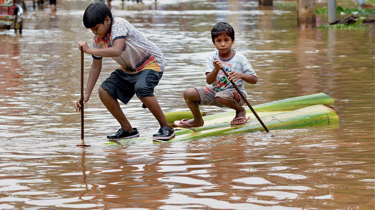 Two boys crossing a flooded street on a raft made of banana tree trunk in Guwahati on Wednesday. 