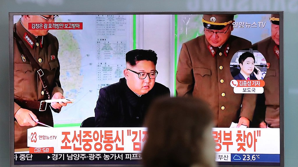A woman walks by a TV screen showing a local news program reporting about North Korean military’s plans to launch missiles into waters near Guam, with an image of North Korean leader Kim Jong Un, at Seoul Train Station in Seoul, South Korea.